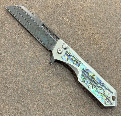 Heretic Knives Jinn Manual Knife – Titanium Chassis, Vegas Forge Herringbone Damascus, Hand Ground Blued Blade, Abalone Inlays – Serialized – Made in USA (S2A-01-0000002H)